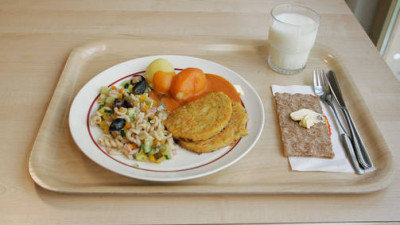 En bricka där det står en tallrik med mat, ett glas mjölk och en knäckebrödsmacka.