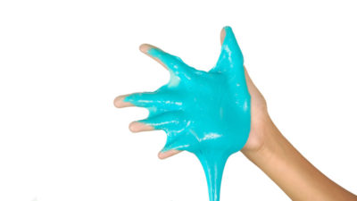 Hand med blågrönt slajm som rinner.