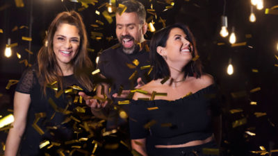 Farah. Kalle och Molly skrattar och ler. De har svarta kläder på sig och det regnar ner guldkonfetti över dem.