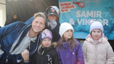 Artisterna Samir och Viktor ler mot kameran tillsammans med tre barn framför en plansch det står Samir & Viktor på.