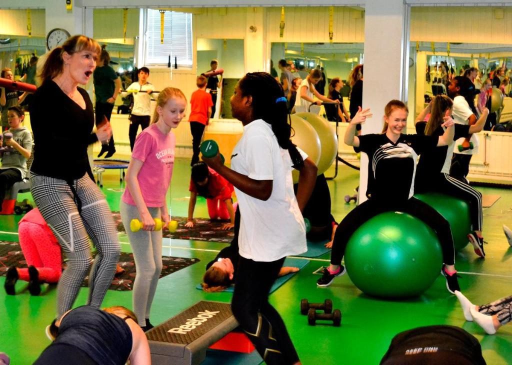 Tre barn och en vuxen tränar styrka på ett gym.