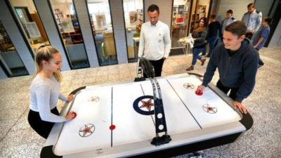 Elever står och spelar lufthockey.