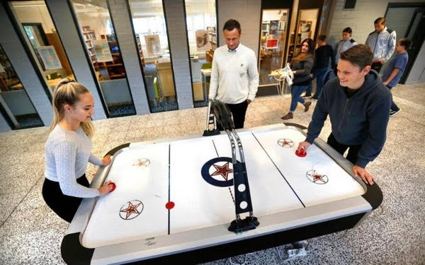 Elever står och spelar lufthockey.