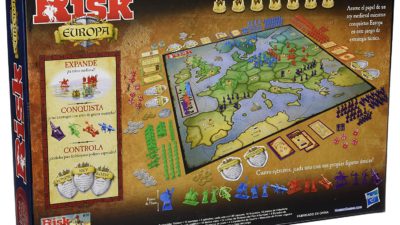 Kartongen med spelet står på högkant. På framsidan syns spelplanen som det ligger massa kort runtom.