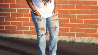 En person med hål på sina jeans står utomhus