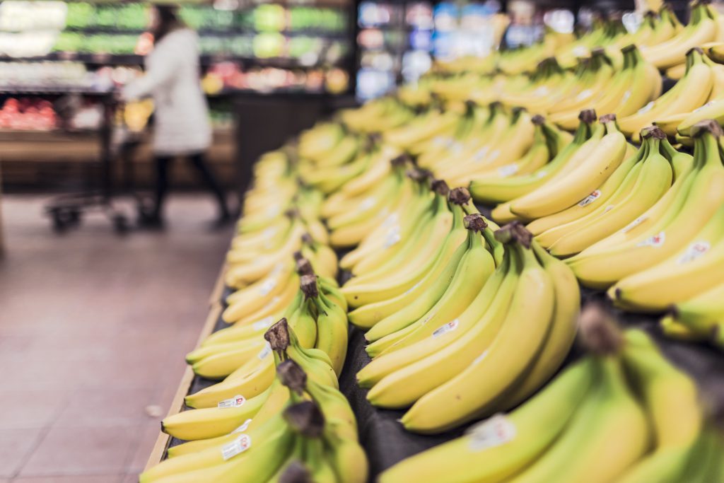 Bananer ligger uppradade snyggt på en hylla i en butik.