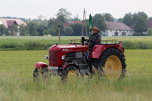 En bonde åker en röd traktor.