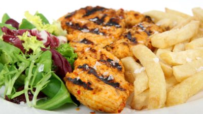 sallad, kött och pommes ligger på en tallrik.