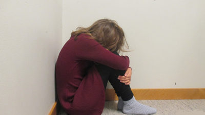 Foto på elev som gömmer ansiktet i knät.