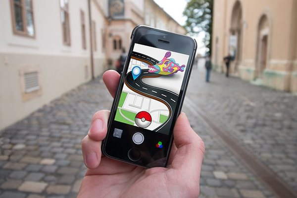 En mobiltelefon med Pokémon go i förgrunden och en gata i bakgrunden.